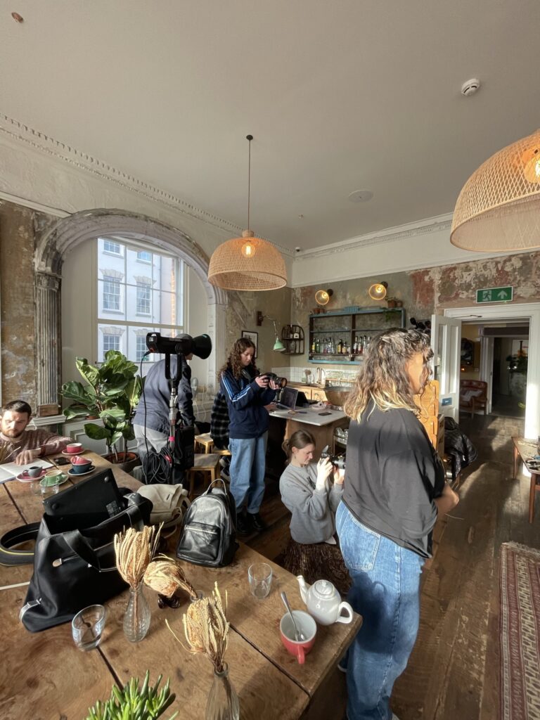 A behind the scenes photo of the boomsatsuma team on set at the Artist Residence venue. Students are photgraphing and directing the model